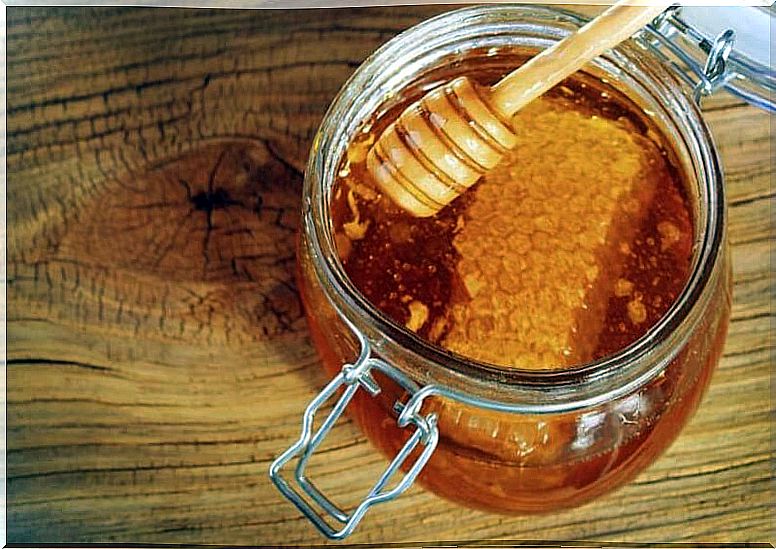 Pot with honey from bees and a piece of honeycomb