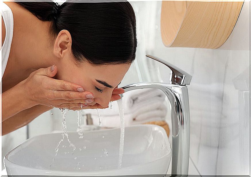 Woman washing her face in the sink.