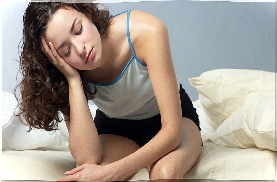 Woman sitting on bed with tired expression