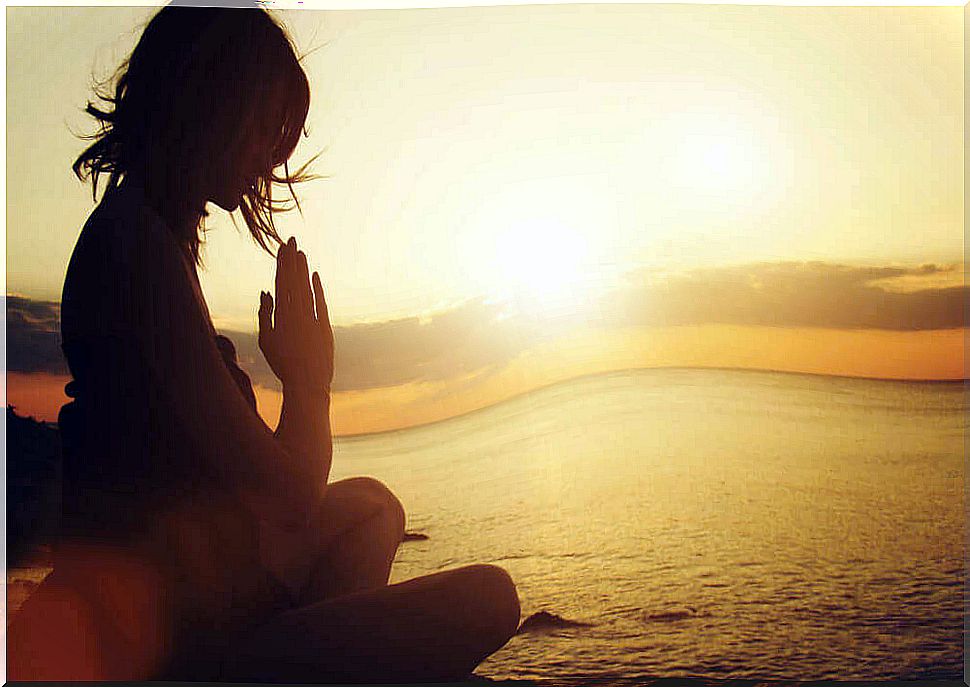 Woman meditating at sunrise.