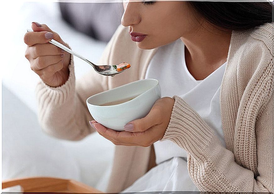 Woman eating bowl of soup.